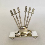 EBERLE - Petisqueira em metal espessurado a prata, com base retangular com seis unidades, pegador em bolas. Med.: 10cm de altura e 9cm de largura.