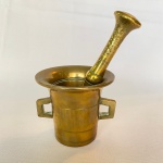 Almofariz com alça e pistilo em bronze polido. Med.: 16cm de altura e 9,5cm de diâmetro.