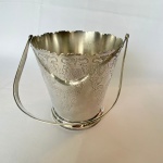 PRATA REGIA 90 - Balde de gelo com alça em metal espessurado a prata, bordas e corpo decorado com volutas e arabescos. Med.: 13cm de altura e 12cm de diâmetro. Alça quebrada.