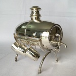 Antigo barril de vinho em metal espessurado a prata com suporte e seis copos. Med.: 21cm de comprimento, 22cm de altura e 15cm de largura.