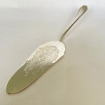 WOLFF PRATA 90 - Espátula de bolo em metal espessurado a prata com detalhes de flores e arabescos. Med.: 26,5cm de largura .