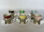 WOLFF - Conjunto com seis xícaras para café de Porcelana Mauá cores diversas e frisos dourados, bases e pires em metal espessurado a prata. Med.: 5cm de altura e 4,5cm de diâmetro.