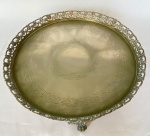 Salva redonda em metal, com detalhes cinzelados, bordas vazadas e três pés em garras. Med.: 31cm de diâmetro. Apresenta desgastes