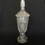 Bomboniere de cristal  europeu translúcido lapidado com estrelas e tampa com pegador facetado. Med.: 32,5cm de altura e 10cm de diâmetro. Pé com parte colada e apresenta bicados.
