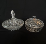 Lote com 2 (duas) bombonieres de cristal translúcido lapidado com tampas e pegador, um deles de metal com argola. Med.: 15cm de altura e 15,5cm de diâmetro. Menor com um pequeno bicado na borda.