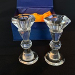 Par de castiçais de cristal facetado com detalhe de bola no meio. Med.: 11,5cm de altura. Possui restauros e um com base rachada. Acompanha caixa original.