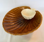 Petisqueira em formato de concha com suporte para molho de cerâmica em tom marrom com branco. Med.: 30x28cm de largura e 8,5cm de altura. Possui restauro no suporte para molho