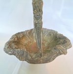 Antigo centro de mesa em metal com alça em formato de cesta, decorado com volutas e arabescos. Med. 30cm de diâmetro. Apresenta desgastes, amassados e perda na borda.