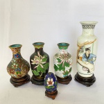 Lote com 5 peças, sendo: Três pequenos potes em metal com closonê e peanhas em madeira med, 10cm de altura; Um ovo em cloisonne com peanha de madeira, med. 5cm de altura (com desgaste na parte superior do ovo) e Um vaso em porcelana com decoração pintada a mão, com peanha em madeira, med. 14cm (apresenta restauro e bicado na borda.