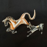 Lote com 2 (duas) esculturas de vidro, sendo: Uma representando cavalo em vidro translúcido com parte interna nas cores marrom e branco med. 16cm e uma representando cachorro (falta calda). 8cm