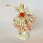 Antiga bailarina em porcelana alemã, vestido decorado com flores, med. 11cm de altura - Apresenta restauro no pé esquerdo.