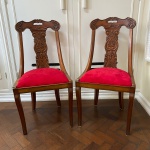 Par de cadeiras em madeira com detalhes esculpidos e forro de veludo vermelho. Med.: 95cm de altura, 48cm de largura e 45cm e comprimento.