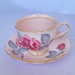 COLCLOUGH BONE CHINA - Antiga xícara para chá em porcelana inglesa na cor rosa decorada com rosas e frisos dourados. med.: 14cm de diâmetro o pires, 8,5cm diâmetros a xícara X 6,5cm de altura. Apresenta restauro