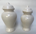 2 potes  com tampa de cerâmica vitrificada na tonalidade branca. Maior: 11 cm de diâmetro x 23 cm de altura