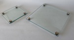 Lote composto de 2 porta doces em vidro translúcido com pés em metal prateado, formatos quadrados. 32 x 32 cm e 20 x 20 cm
