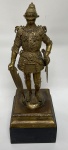 Escultura de latão representando cavalheiro com armadura, rosto provavelmente em resina. 15,5 x 15 cm na base x 45 cm de altura total 