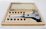 RELÓGIO, um (1) kit de ferramenta com chave de remoção da tampa de caixas de relógios, ajustável ao tamanho da tampa, acondicionado em caixa de madeira.