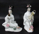 ESCULTURAS - Duas belíssimas esculturas orientais em porcelana vitrificada branca, ricamente detalhadas, representando "Gueixas Musicistas", ornamentadas por rosas e folhas em alto relevo e arremates em pintura à ouro. Medidas: 13 cm de altura, aproximadamente.