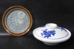 PORCELANA - Lote contendo duas peças em porcelana vitrificada, sendo: A) um prato decorativo em porcelana inglesa da manufatura JOHNSON BROS ENGLAND (marcada no fundo). ricamente decorado com figuras geometrizadas e motivos florais, bordas adornadas com larga faixa na cor marrom, medindo: 17 cm de diâmetro; B) uma tigela com tampa em fina porcelana oriental com esmaltagem nas tonalidades branca e azul, apresenta ornamentação de flores, folhas e filetes, marcada com selo em caracteres no fundo, medindo: 8 cm de altura total x 18 cm de diâmetro (possui dois ínfimos bicado na borda).
