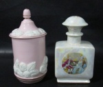 PORCELANA - Duas antigas peças em porcelana vitrificada, sendo: A) um porta talco em porcelana com esmaltagem na tonalidade rosa bebê, com primorosa ornamentação de flores e folhas em alto relevo, arrematado com filetes à ouro, pega da tampa em forma estilizada de pinha, medindo: 15,5 cm de altura x 7 cm de diâmetro; B) um perfumeiro em porcelana com efeito perolizado furta-cor, decorado com cenas galantes e motivos florais em rica policromia, medindo: 14 cm de altura total x 8 cm de comprimento. Peças com manufaturas marcadas no fundo, conforme fotos extras.