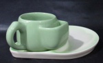FAIANÇA - Xícara para chá com seu pires com prato para biscoitos acoplado, confeccionados em faiança vitrificada nas tonalidades verde e creme. Medidas: xícara: alt 7 cm x larg total 11 cm/ pires: comp 21,5 cm x larg 17 cm. Pires com um ínfimo bicado na borda.