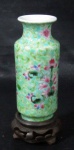 PORCELANA - Um pequeno vaso em porcelana chinesa vitrificada branca, ricamente decorado com motivos vegetalistas em policromia, apoiado sobre peanha em madeira, marcado no fundo com caracteres, conforme foto extra. Medidas: 11 cm de altura total x 3 cm de diâmetro da borda.