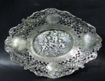 PRATA DE LEI - Belíssima salva oval em prata de lei, ricamente repuxada e cinzelada em relevo, com interessante cena de Putinos ao centro, seguida de rica ornamentação de motivos vegetalistas vazadas,, contraste ilegível, medindo: 17,5 cm de comprimento x 11,8 cm de largura. Peso: 116,20 gramas.