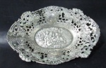 PRATA DE LEI - Belíssima salva oval em prata de lei, ricamente repuxada e cinzelada em relevo, com interessante cena de Putinos ao centro, seguida de rica ornamentação de motivos vegetalistas vazadas,, contraste ilegível, medindo: 16,5 cm de comprimento x 11,8 cm de largura. Peso: 97,50 gramas.