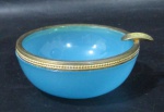 OPALINA - Um cinzeiro em opalina na cor azul, guarnecido com bronze nas bordas, medindo: alt 3 cm x diam 8 cm.