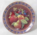 PORCELANA GERMER - Um prato decorativo em porcelana vitrificada branca, ricamente pintado à mão, decorado com frutos e folhas em exuberante policromia, com bordas filetadas à ouro, marcado "Germer F10" e "Bia Porcelanas" no fundo, medindo: 24,5 cm de diâmetro. Vide fotos.