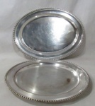 METAL PRATEADO - Duas travessas para baquete em metal espessurado a prata, com formatos distintos, sendo uma redonda e uma ovalada, com bordas ricamente trabalhas com perolados. Medidas: maior: comp 51 cm x larg 38 cm/ menor: diam 39 cm. Necessitam de banho.