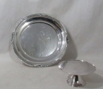 METAL PRATEADO - ST JAMES - Duas fruteiras em metal espessurado a prata, sendo uma mini apoiada sobre pé elevado bolacha da manufatura ST JAMES (marcada no fundo); e uma com bordas ricamente trabalhadas com canelados, conchas e volutas, com base tripoide com pés cinzelados em garras. Medidas: maior: 32 cm de diâmetro/ menor: 7 cm de altura x 14,5 cm de diâmetro.