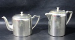 METAL PRATEADO - BELPRATA - Um bule e uma leiteira em metal espessurado a prata, com tampas articuladas e alças com parte superior ligeiramente abauladas, marcados no fundo. Medidas: maior: alt total 14,5 cm x larg total 18 cm/ menor: alt total12 cm x larg total 20,5 cm.