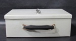 DIVERSOS - Antiga caixa em ferro patinado no formato de maleta, alça superior para transporte em plástico rígido, possui chave. Medidas: alt 11,5 cm x comp 32 cm x larg 21 cm. Com marcas do tempo/ uso.