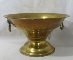 BRONZE - Uma champanheira em bronze dourado, alças laterais articuladas ricamente cinzelados iniciando com cabeça de leão e finalizando com volutas e concheado, apoiada sobre pé bolacha, medindo: 20 cm de altura x 34,5 cm de diâmetro. Com marcas do tempo.