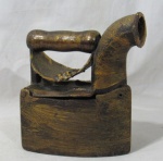 DIVERSOS - Antigo ferro de passar roupa à brasa confeccionado em ferro fundido com pátina em toques de folhas de ouro velho, punho em madeira torneada, modelo chaminé. Medidas: alt 20,5 cm x comp 18 cm.