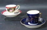 PORCELANA - Duas xícaras com seus respectivos pires, de coleção, em fina porcelana vitrificada nas tonalidades branca e azul cobalto, pintados à mão, com luxuosa decoração de flores e folhas em policromia e vasta douração, guirlandas de volutas e arabescos, generosos filetes e frisos em pintura à ouro, bordas adornadas com faixas esmaltadas nas cores rosa e dourado, marcados no fundo, conforme fotos extras. Medidas: maior: xícara: alt 6 cm x diam 6,8 cm/ pires: diam 12,7 cm/ menor: xícara: alt 5,5 cm x diam 6,2 cm/ pires: diam 11,5 cm. Uma apresenta pequenas falhas na pintura.