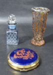 DIVERSOS - Lote contendo três peças, sendo: A) um perfumeiro em cristal em double color translúcido e azul, com bojo ricamente lapidado com motivos geométricos losangonais, tampa facetada; B) um pequeno vaso em cristal na cor rosa, moldado em formato geometrizado oitavado, ornamentado com flores e folhas em pintura à prata, bordas onduladas, fundo estrelado; C) uma caixa porta pó em metal dourado, com tampa em porcelana vitrificada na tonalidade azul cobalto manufaturada LIMOGES, encimada com cena galante em pintura à ouro, guarecida com espelho na parte interna (possui marcas do tempo). Medidas: maior: 10,5 cm de altura/ menor: 7,5 cm de diâmetro.