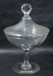 CRISTAIS SAINT LOUIS - Elegante compoteira em finíssimo e translúcido cristal francês, delicadamente lavrado à mão, no estilo vitoriano com frisos e guirlandas de flores e folhas, pega da tampa em forma globular ricamente facetada, haste lisa, sobre base circular. Medidas: 24 cm de altura total x 15,5 de diâmetro da borda.