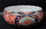 PORCELANA IMARI - Um centro de mesa/ fruteira em porcelana japonesa vitrificada e ricamente policromada, descorda com motivos vegetalistas e volutas realçados á ouro, bordas movimentadas adornadas com filetes na cor marrom, marcado com selo em caracteres no fundo. Med. alt 8 cm x diam 19 cm.