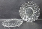 VIDRO - Dois pratos para bolo em vidro translúcido, sendo um profusamente lapidado com gotas e fundo estrelado, e um delicadamente lavrado à mão, com motivos florais e volutas, com bordas onduladas. Medidas: maior: 35 cm de diâmetro/ menor: 33 cm de diâmetro.