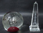 CRISTAIS / MURANO - Dois pesos de papel, sendo um em murano e um em cristal translúcido, moldados em feitios diferenciados, ricamente elaborados com interior com bolhas, base bordô e Torre Eiffel. Medidas: maior: 13,5 cm de altura / menor: 9 cm de altura.