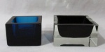 MURANO - Duas peças em murano, apresenta formato quadrado, sendo um porta clips na cor azul e um cinzeiro translúcido com interior negro. Med. maior: alt 5 cm x larg 9,5 cm/ menor: alt 5,2 cm x larg 7,7 cm. Porta clips com bicado na borda.