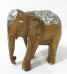 ESCULTURA - Escultura em madeira representando elefante, faixa do corpo e da cabeça decorados com metal prateado ricamente cinzelado com elementos vegetalistas. Medidas: 14 cm de altura 14 cm de comprimento, aproximadamente.