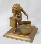 MEMORABILIA FUMAGEIRA - Antigo Cinzeiro, Porta Caixa de Fósforos e Porta Cigarros, com escultura de Homem Corcunda, confeccionado em bronze patinado, sobre base em formato quadrado. Med. alt 13,5 cm x larg da base 13 cm. Falta porta caixa de fósforos. Vide fotos extras.