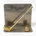 METAL PRATEADO - Porta papel com base em metal prateado e adornos reproduzindo Taco e Bola de Golfe em metal dourado, medindo: 9,5 cm de altura x 11 cm de comprimento.