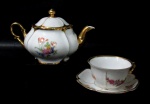 PORCELANA MAUÁ - Um bule e uma xícara com seu pires para chá, em porcelana nacional vitrificada branca, elegantemente decorados com motivos vegetalistas em rica policromia, alças vazadas finalizando em volutas, pega da tampa em forma estilizada de flor, guarnecidos com exuberante pintura feita à ouro nas bordas, alças, bico e pega da tampa, marcados no fundo. Medidas: bule: alt total 13,5 cm x larg total 22,5 cm/ xícara: alt 5 cm x diam 9,3 cm/ pires: diam 13,3 cm. Xícara com um ínfimo bicado na borda.