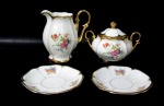 PORCELANA MAUÁ - Uma leiteira, um açucareiro e dois pires, em porcelana nacional vitrificada branca, elegantemente decorados com motivos vegetalistas em rica policromia, alças vazadas finalizando em volutas, pega da tampa em forma estilizada de flor, guarnecidos com exuberante pintura feita à ouro nas bordas, alças, bico e pega da tampa, marcados no fundo. Medidas: leiteira: alt 13 cm x larg total 12,5 cm/ açucareiro: alt total 10 cm x larg total 15 cm/ pires: diam 13,3 cm.