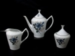 PORCELANA POZZANI JUNDIAÍ - Um bule para café, uma leiteira e um açucareiro em porcelana nacional com esmaltagem branca, decorados com flores e folhas em policromia, alças vazadas, pegas das tampas em formato obcônico encimadas com vasta douração, arrematados com filetes à ouro, marcados no fundo. Medidas: maior (bule): alt total 18,5 cm x larg total 20 cm/ menor (leiteira): alt 11 cm x larg total 13 cm. Com pequenas falhas na douração.