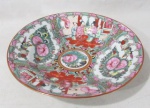 PORCELANA - Um prato fundo, de coleção,  em porcelana chinesa vitrificada branca, fabricado em Macau, no padrão família rosa, estilo cantonês, pintados à mão, com rica ornamentação policromada de cenas do gênero, arabescos, volutas e elementos vegetalistas, arrematados com generosos filetes e realces à ouro, marcado no fundo, conforme foto extra. Medida: 23 cm de diâmetro.